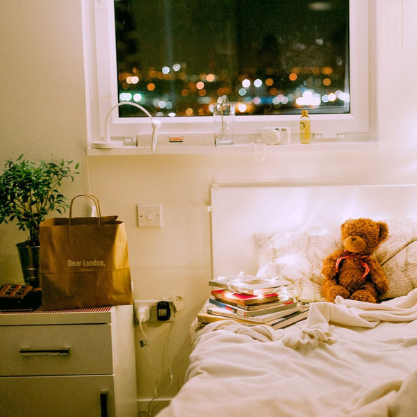 a small bedroom with fairy lights and a teddy bear