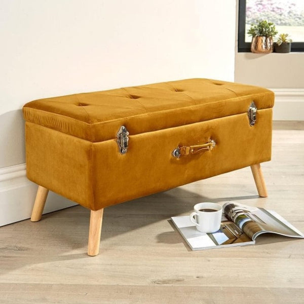 A mustard yellow velvet ottoman bench with chesterfield button details