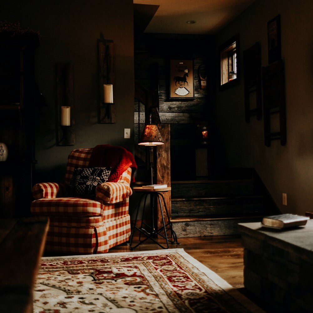 a dark living room with a comfortable fabric chair